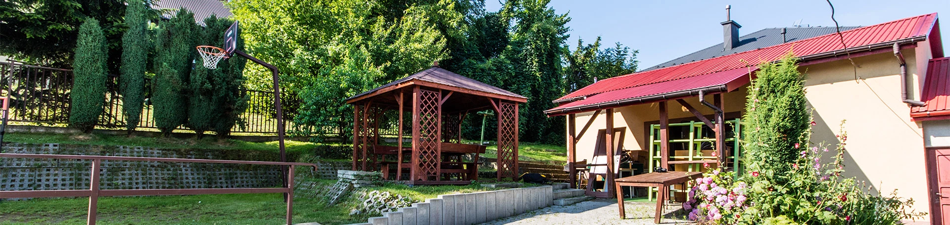 Widok na podjazd z kostki brukowej, budynek gospodarczy i altankę.